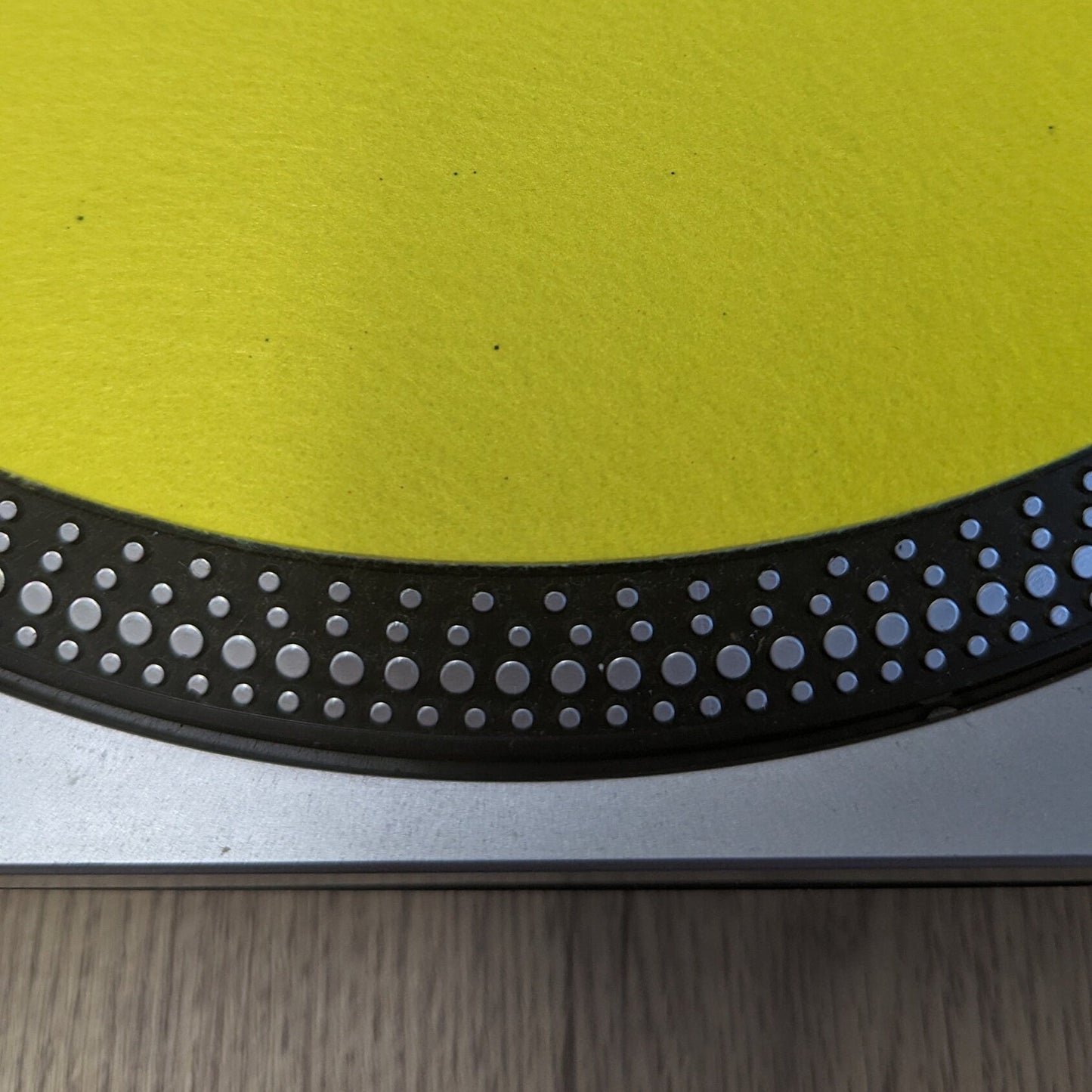 a close up of a Yellow slip mat with a small metallic object on top, on a turntable