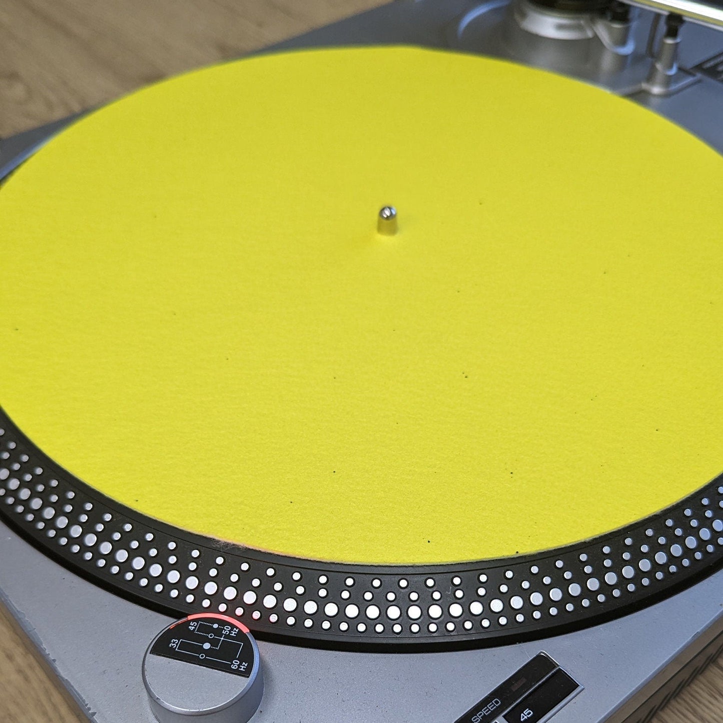 Turntable with a yellow turntable mat on a wooden surface
