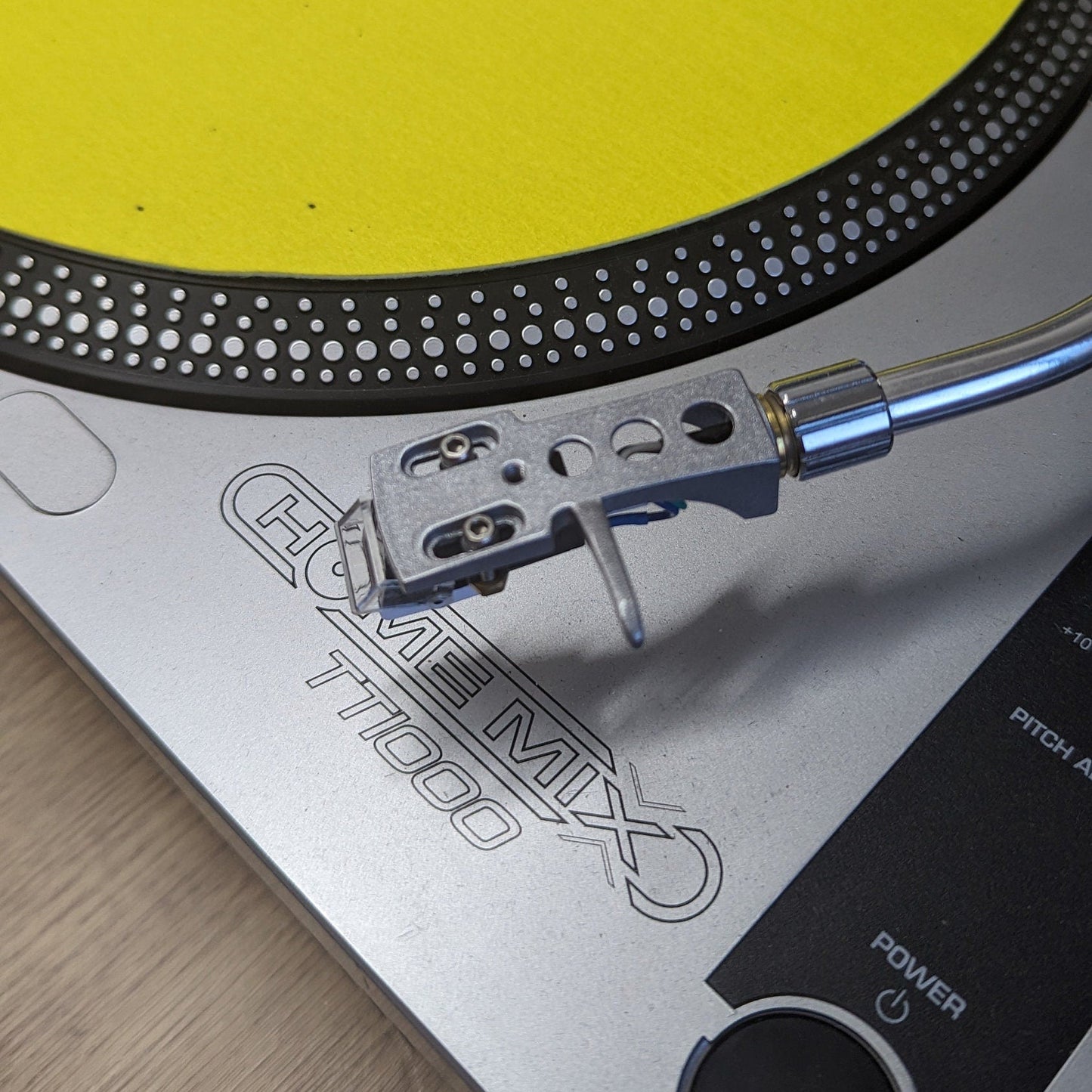 Turntable with a yellow platter on a wooden surface