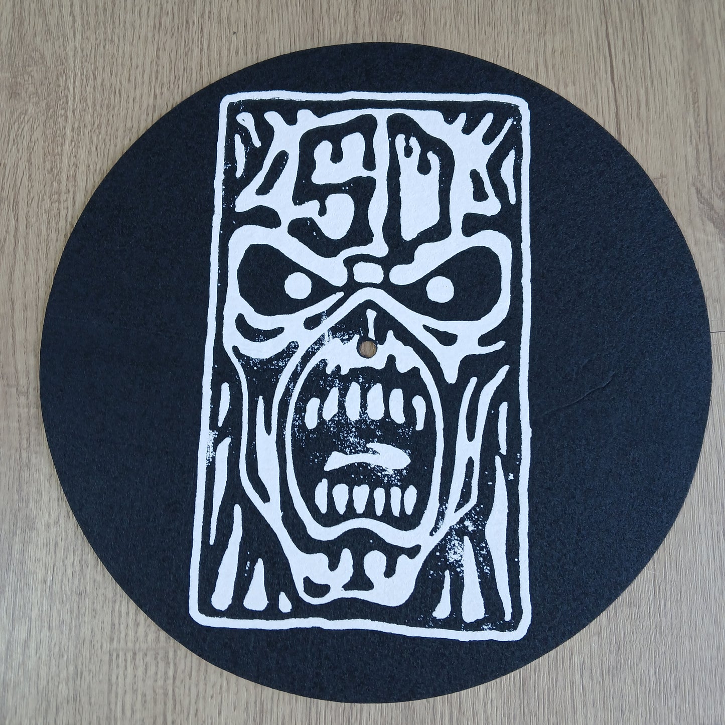 Black circular mat with white abstract design on a wooden surface