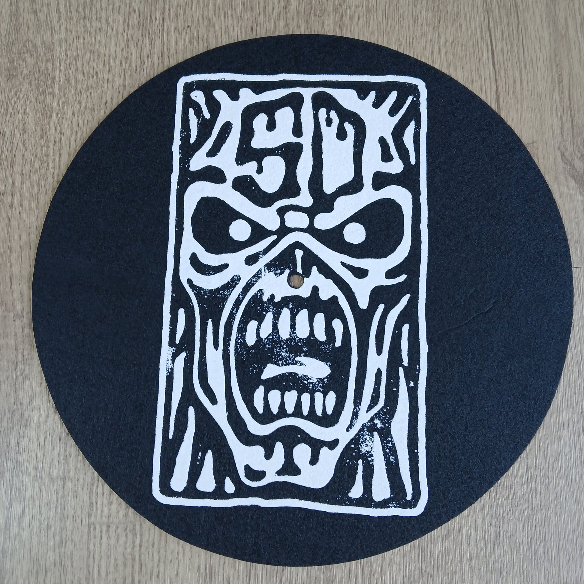 Black circular mat with white abstract design on a wooden surface