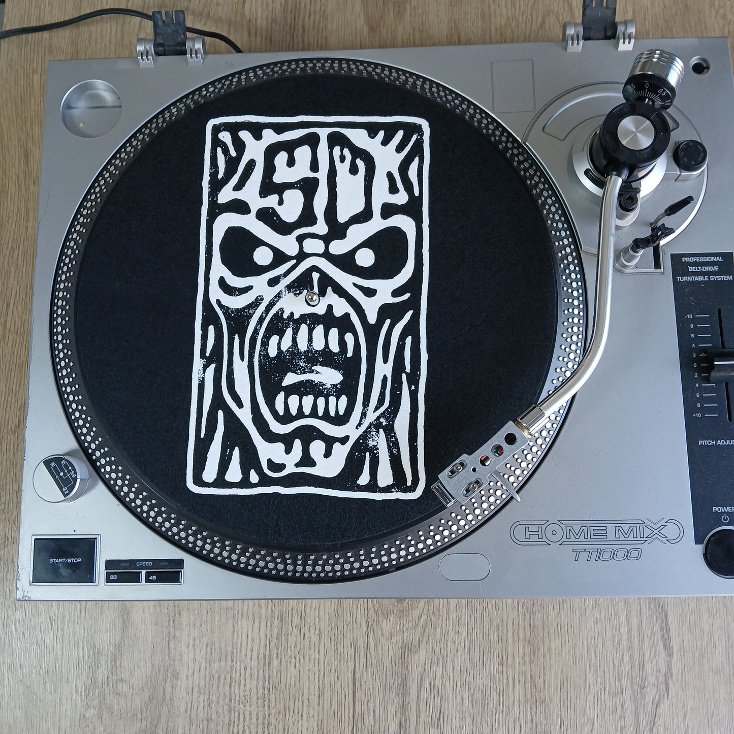 Turntable with a decorative Iron Maiden slipmat on a wooden surface