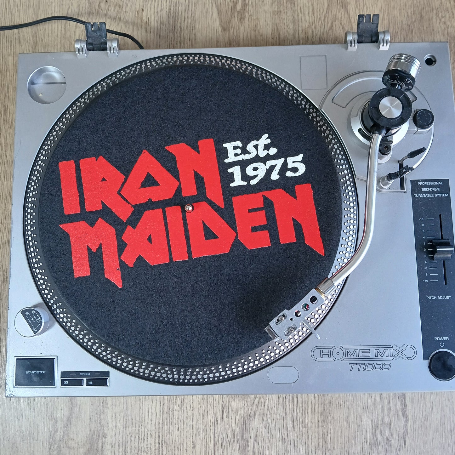 Turntable with Iron Maiden official slipmat logo on a wooden surface