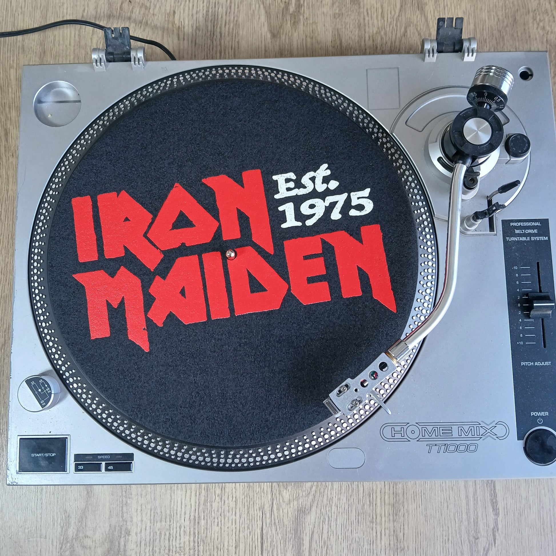 Turntable with Iron Maiden official slipmat logo on a wooden surface