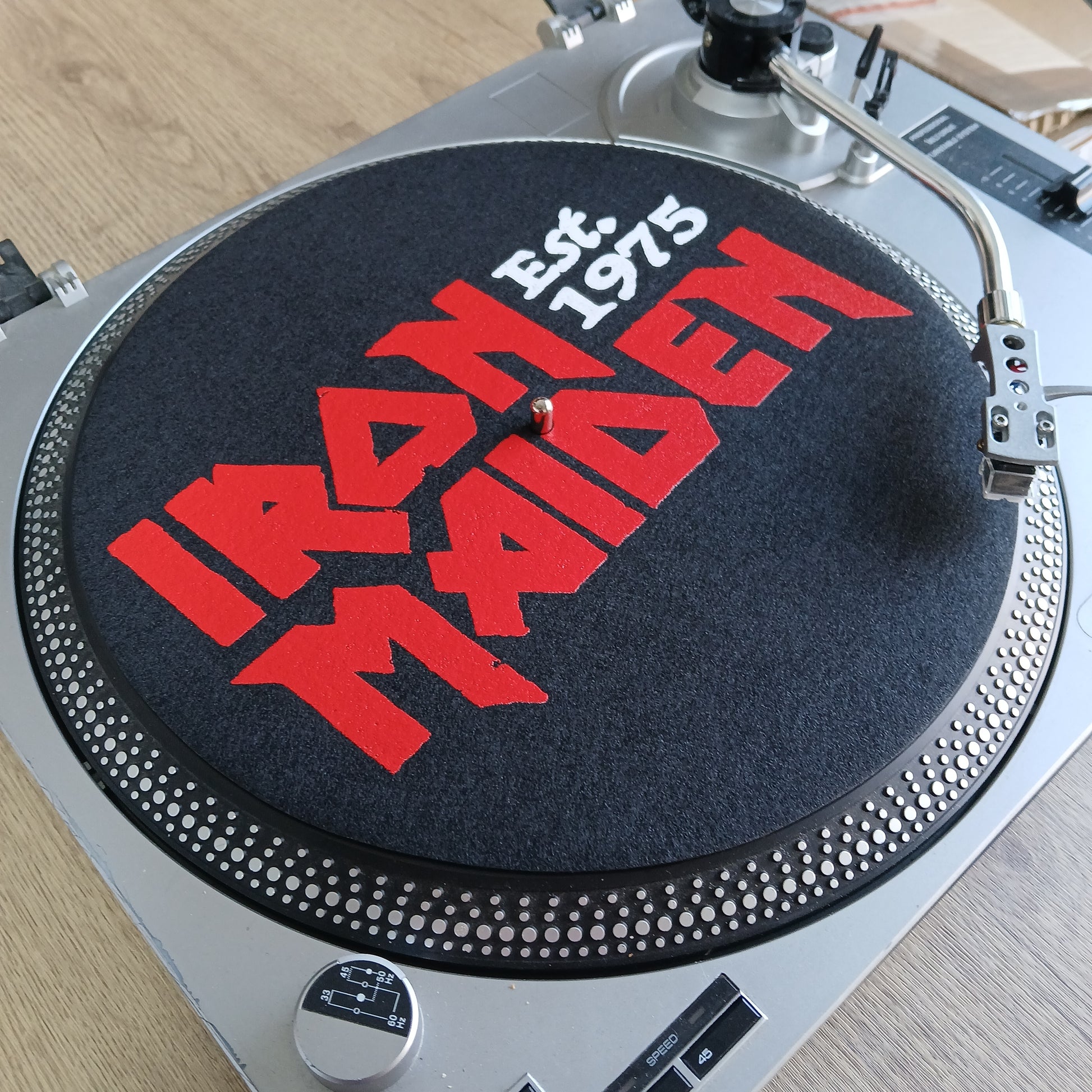DJ turntable with red and white Iron Maiden logo on a wooden surface
