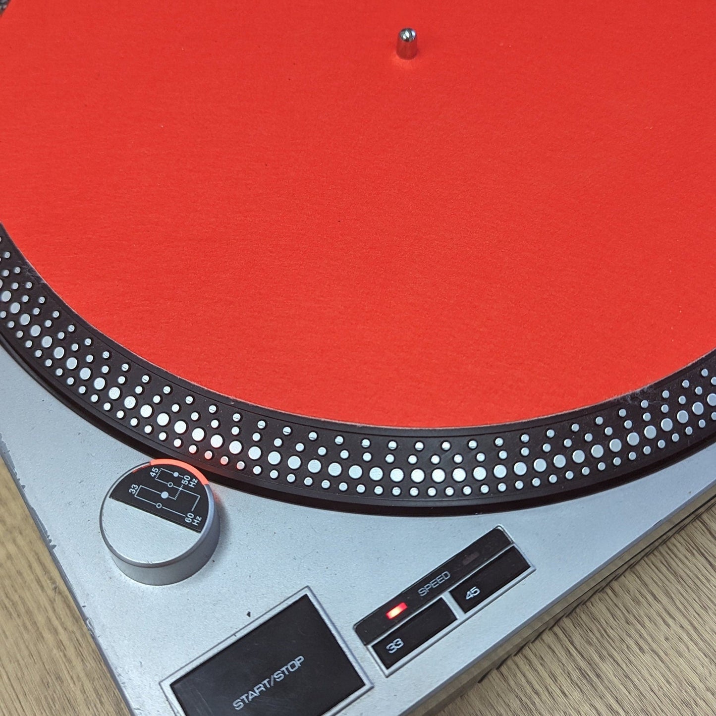 Turntable with a red platter on a wooden surface