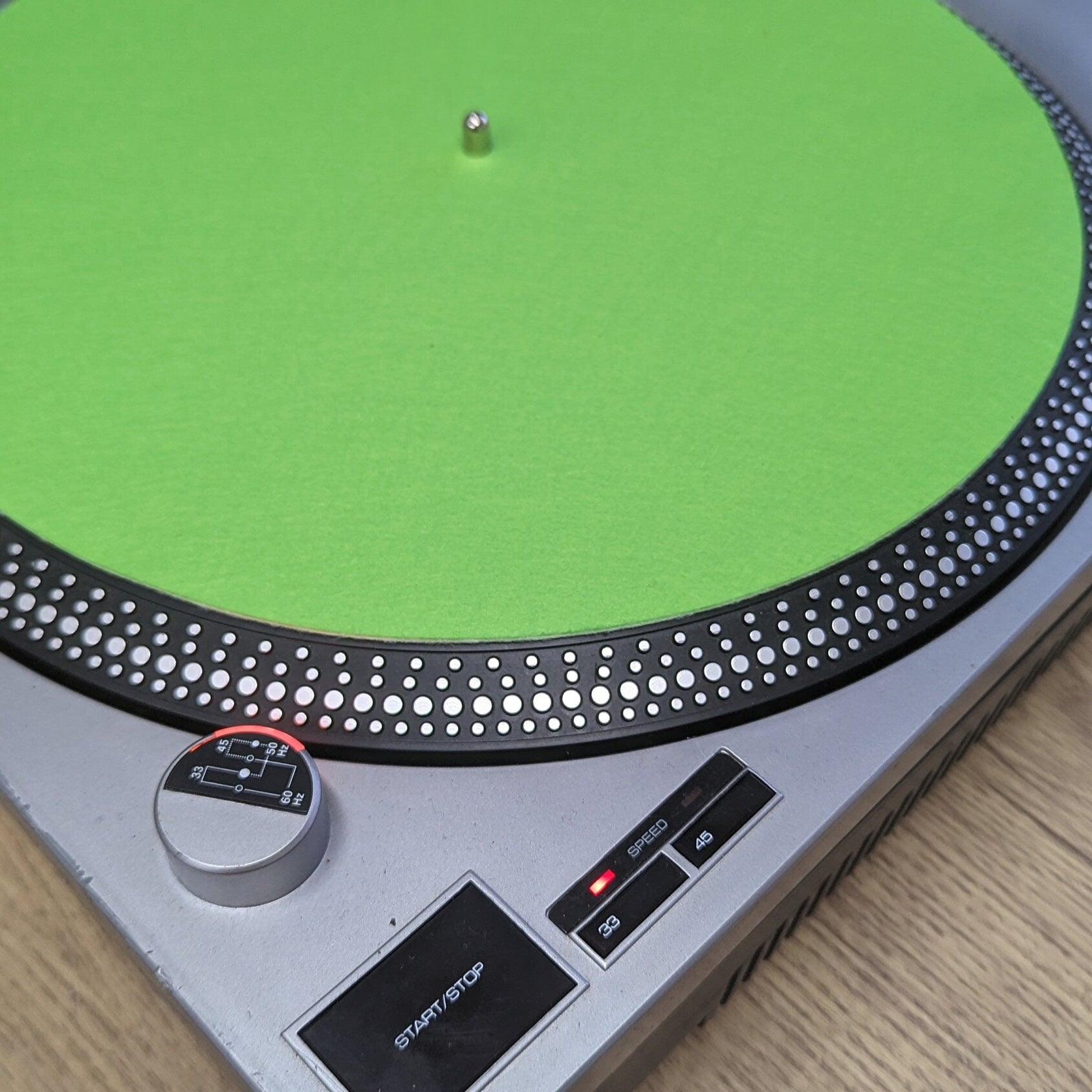 Turntable with a green platter on a wooden surface