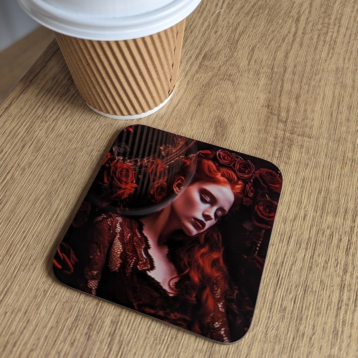 Coaster with a design of a woman's face on a wooden surface next to a coffee cup.