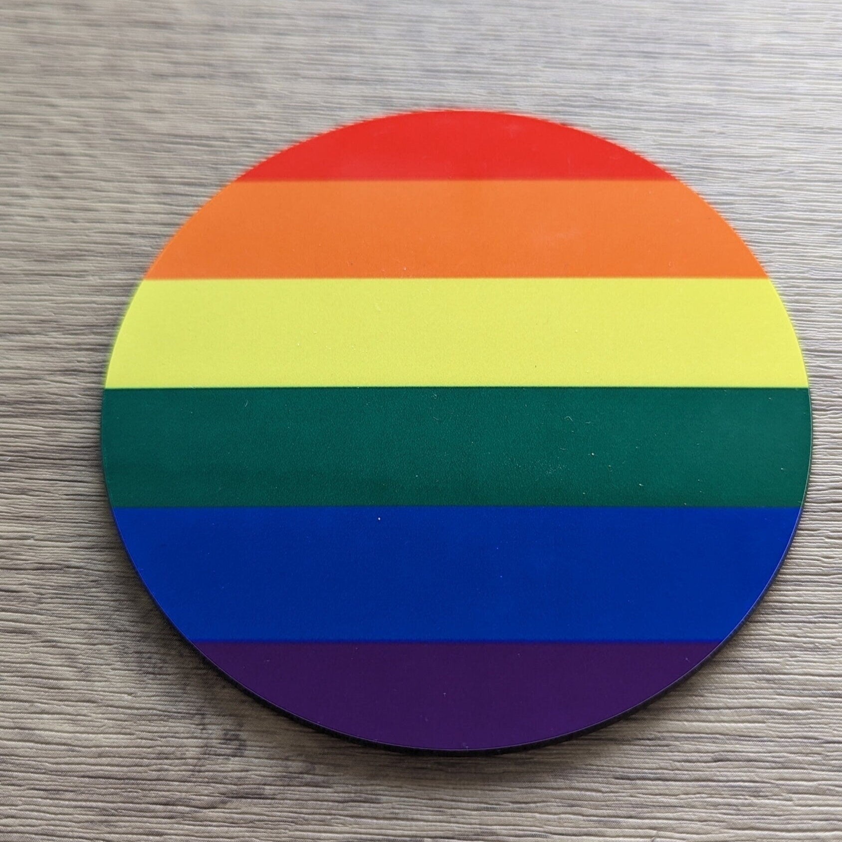 Round rainbow coaster on a wooden surface